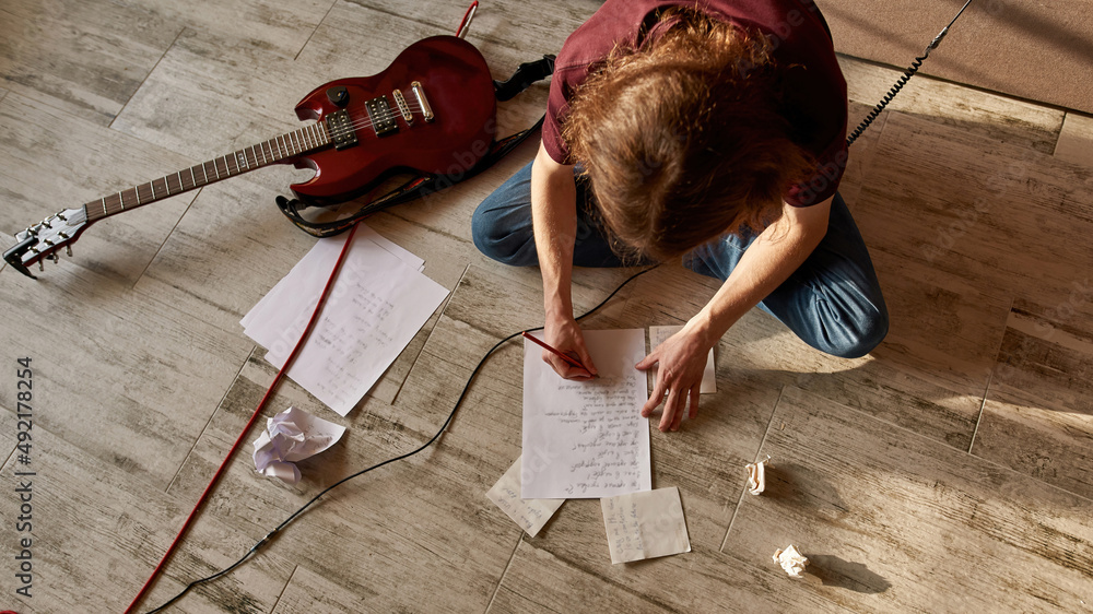 Top view of man writing text of new song on paper - obrazy, fototapety, plakaty 