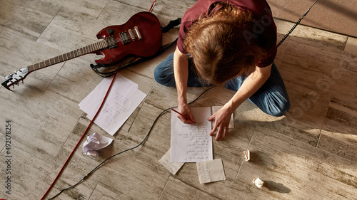 Top view of man writing text of new song on paper