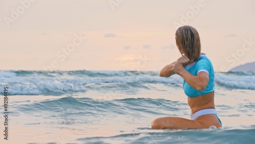 SLOW MOTION GLOW MIST GOLD SUNSET CINEMATIC VIEW  Attractive woman sitting on water sea. Girl in turquoise swimsuit. Freedom paradise holiday vacation summer beach and seaside landscape concept