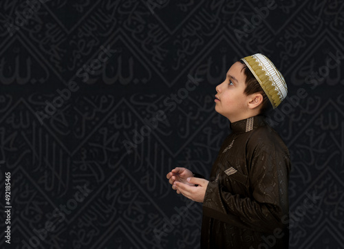 Muslim kid in white traditional clothes, praying at Kaaba in Makkah. High quality photo