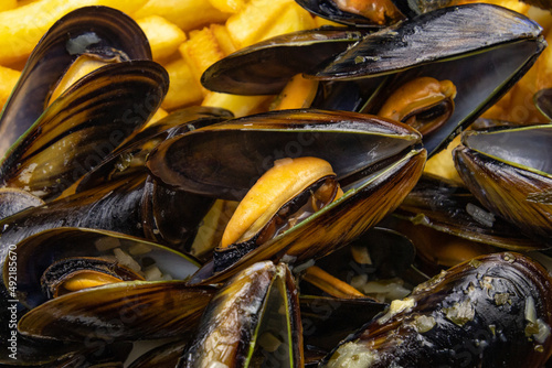 close up of baked mussels with fries on a plate