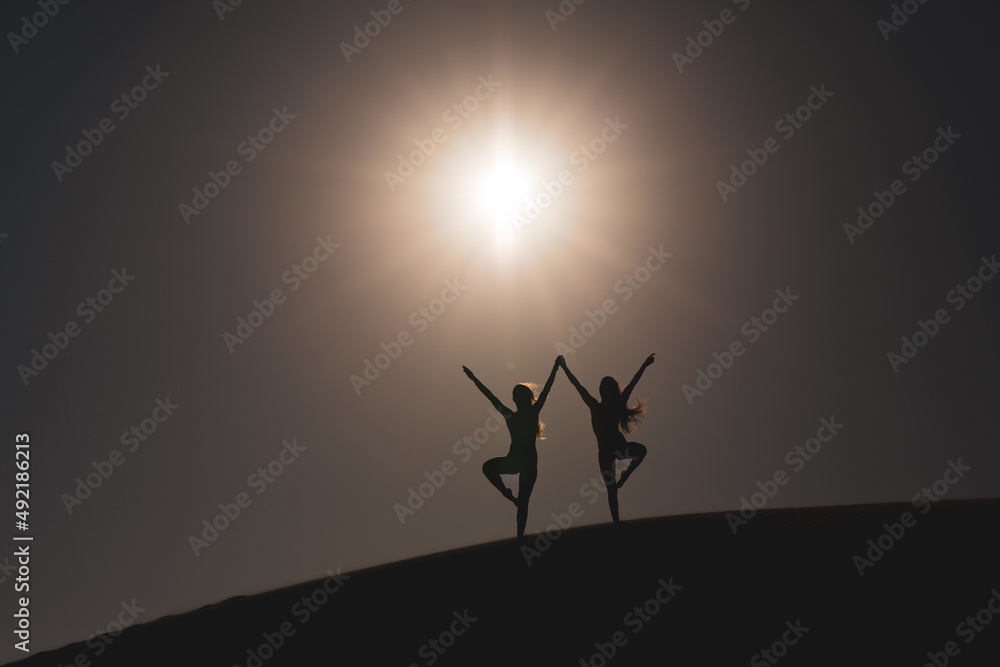 Amigas realizando poses divertidas a contraluz sobre una duna