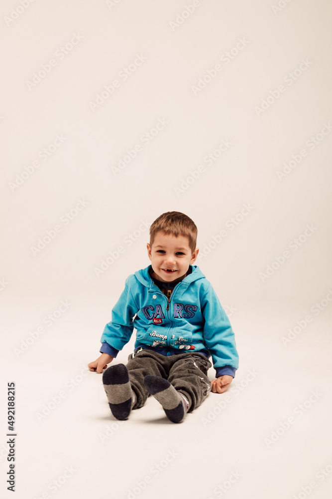 Little boy sits on a white cube and smiles Little boy sits on a white cube and smiles