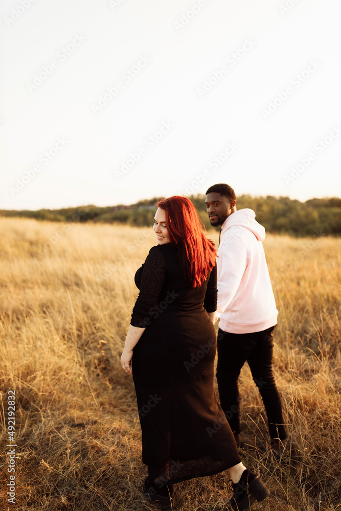 Beautiful couple walking at the field, attractive husband holding hands adorable wife, overjoyed woman smiling, happy family spend time together, weekends outdoors concept Beautiful couple walking at the field, attractive husband holding hands adorable wife, overjoyed woman smiling, happy family spend time together, weekends outdoors concept