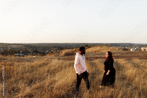 Wonderful couple walking at the field  African American man holding hands lovely white woman  attractive husband with adorable wife spend time together  weekends outdoors concept