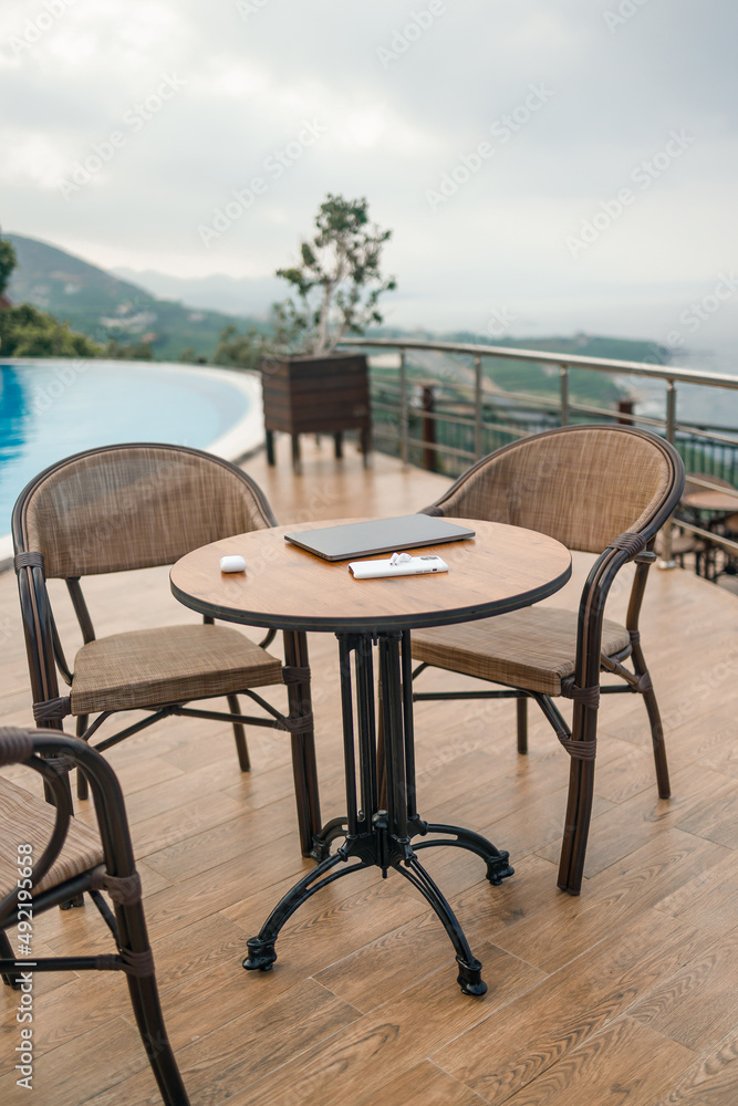 A wooden table on it is a laptop, phone and wireless headphones. Table with modern gadgets