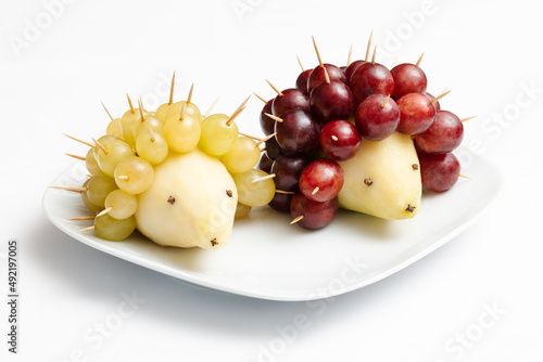 Hedgehogs made of fruits. Pear and grapes on a plate.