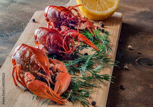 boiled red crayfish with dill and lemons lie on a cutting board 
