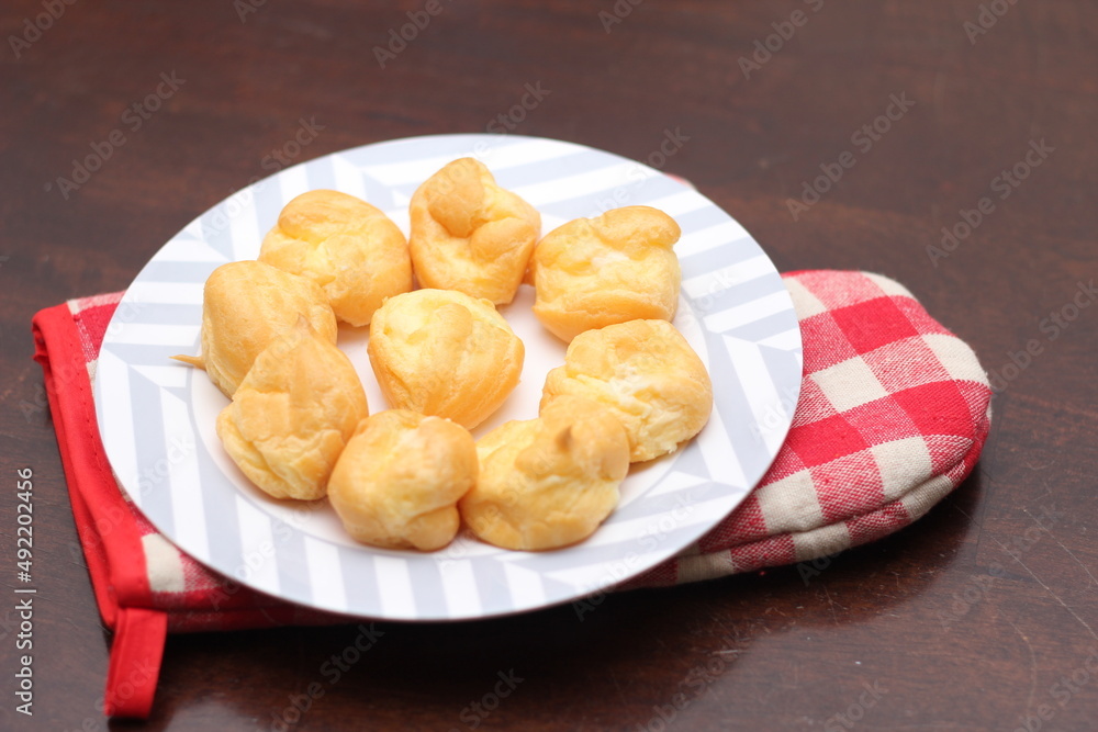 The eclair is placed in a white plate on a wooden table. The eclair is placed in a white plate on a wooden table.