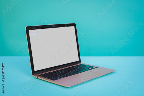 Laptop computer with blank screen on Aztec green paper background.