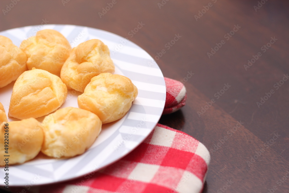 The eclair is placed in a white plate on a wooden table. The eclair is placed in a white plate on a wooden table.