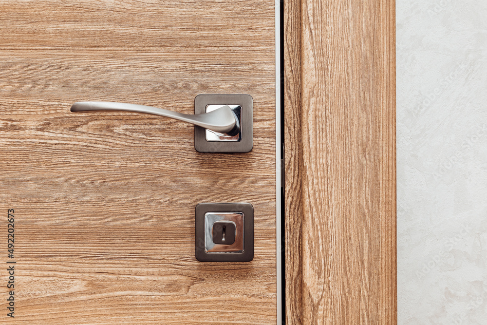 modern metal door handle in a wooden interior door modern metal door handle in a wooden interior door