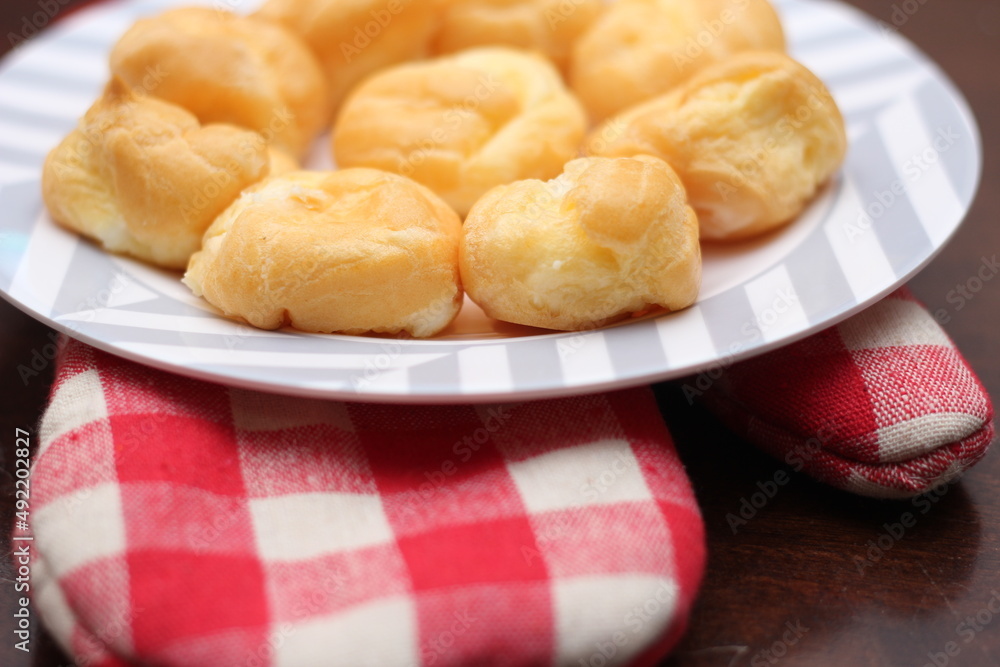 The eclair is placed in a white plate on a wooden table. The eclair is placed in a white plate on a wooden table.