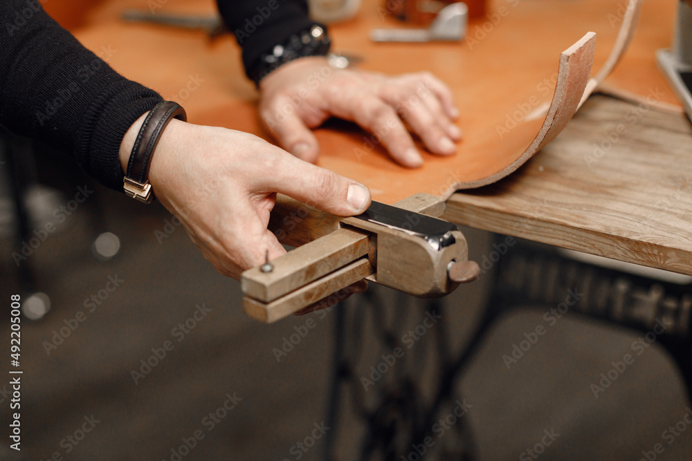 Cropped photo of a leather craftsman hands working on a belt Cropped photo of a leather craftsman hands working on a belt