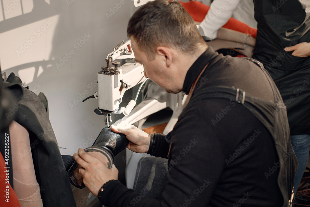 Fototapeta premium Leather craftsman working on a shoe using a special machine