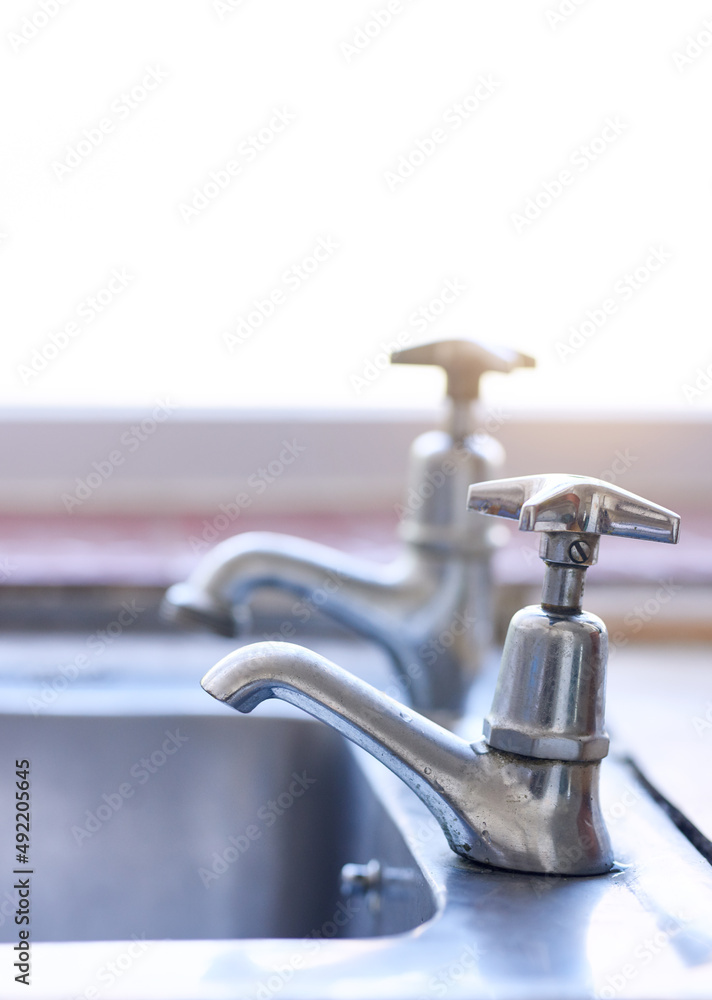 Water is in short supply. Shot of two dripping taps waisting a little bit of water in a basin inside of a house during the day. Water is in short supply. Shot of two dripping taps waisting a little bit of water in a basin inside of a house during the day.