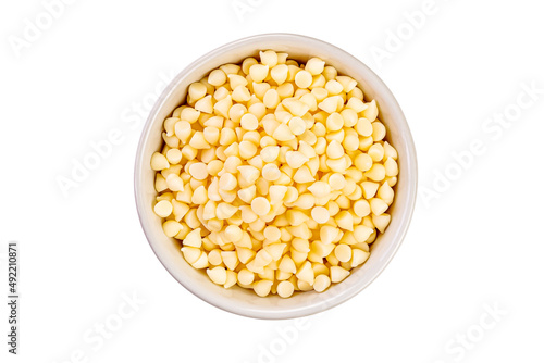 Top view of white chocolate chips in ceramic cup on white background.