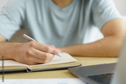 Distance education concept, Teen boy taking notes while studying online with teacher on video call