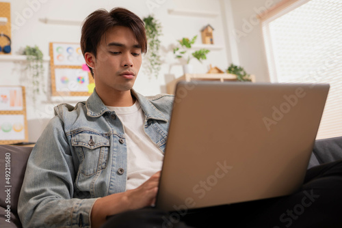 At home, a business asian man types and works online on a desk table with a laptop.