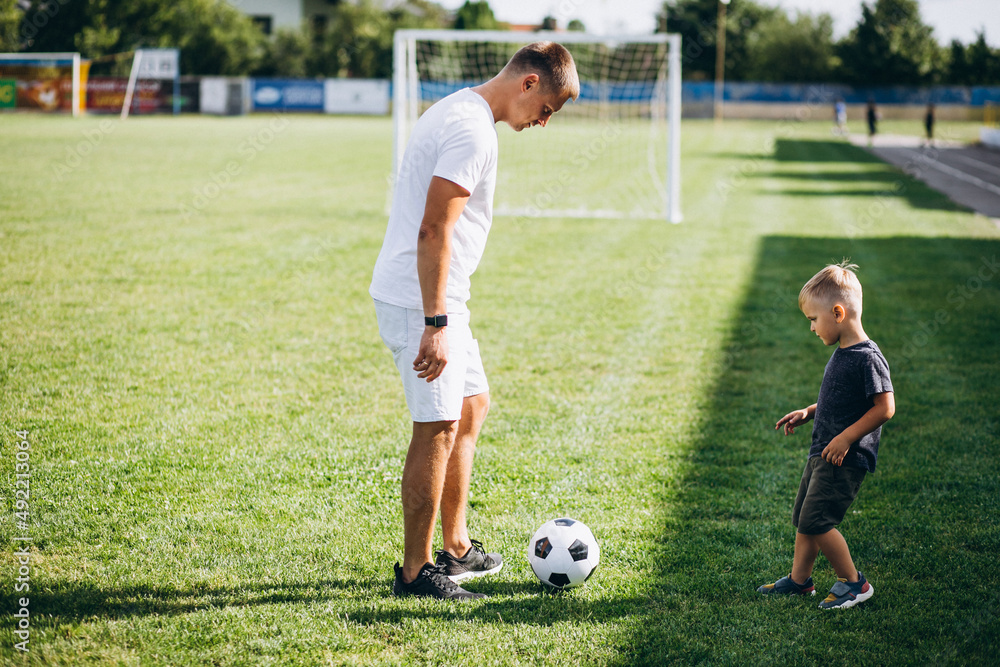 Obraz premium Father with son playing football at the field