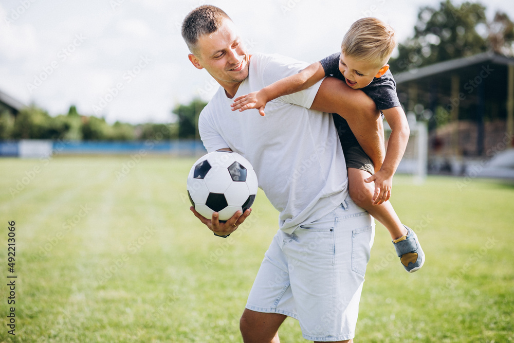 Fototapeta premium Father with son playing football at the field
