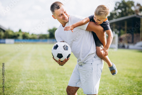 Father with son playing football at the field © Petro