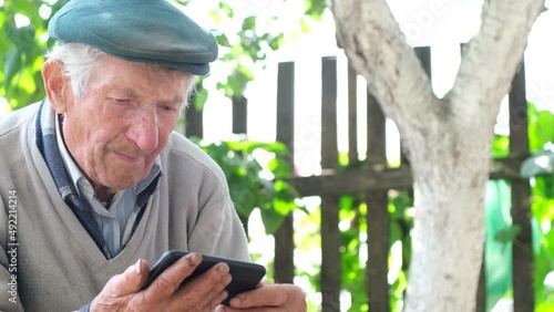 The old grandfather is crying looking at his smartphone. Consequences of Russia's war with Ukraine photo