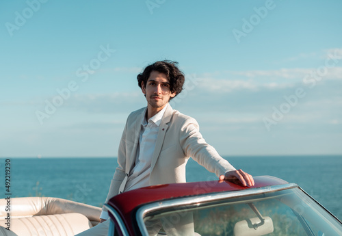 happy Frenchman driving cabriolet car over blue sea, blue sky background