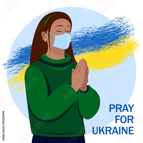 Stop the war. A woman praying against the background of the Ukrainian flag