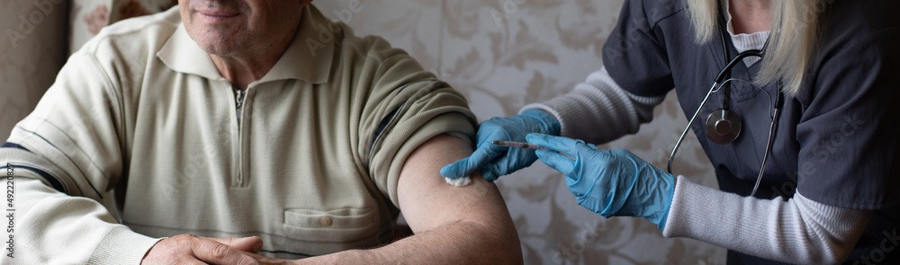 Doctor preparing vaccination shot to elderly patient by holding syringe at home - concept of home health check to seniors during coronavirus covid-19 pandemic Doctor preparing vaccination shot to elderly patient by holding syringe at home - concept of home health check to seniors during coronavirus covid-19 pandemic