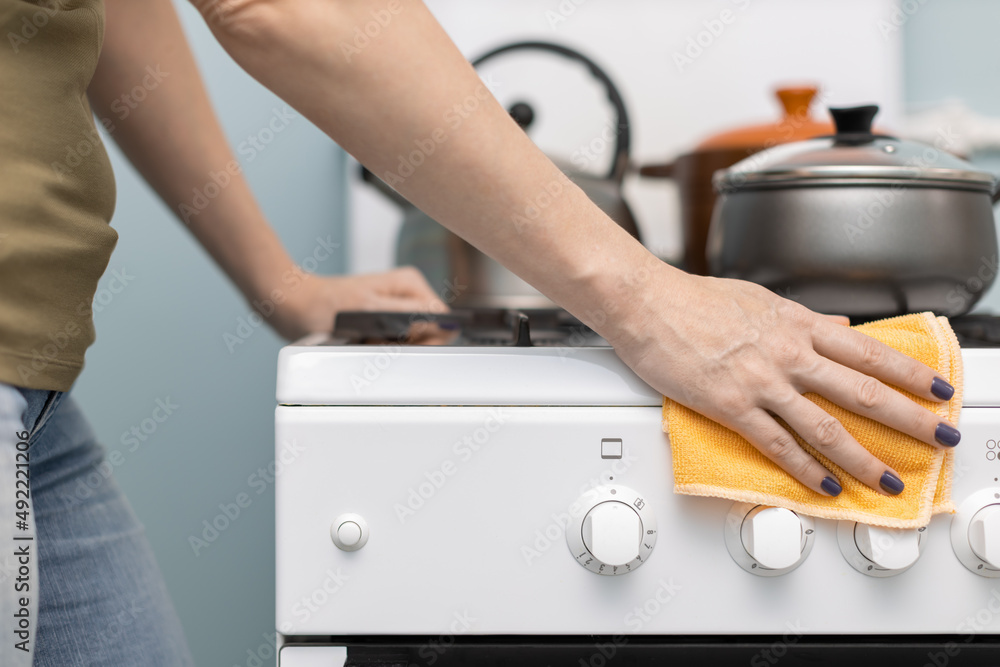 girl wipes the gas stove with a rag girl wipes the gas stove with a rag