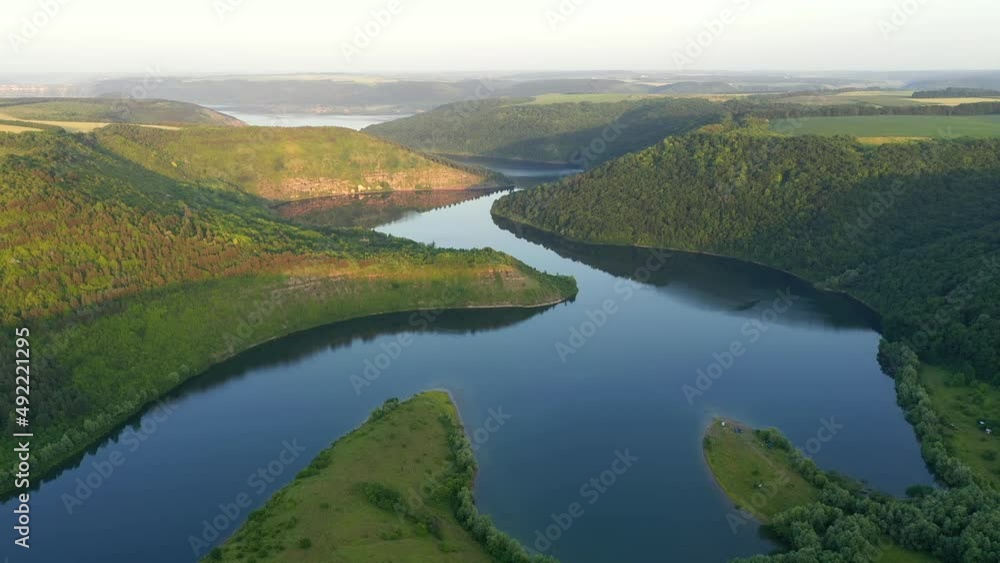 Panoramic view of the meandering river flowing through the green hills from a bird's eye view. Filmed in UHD 4k video. Panoramic view of the meandering river flowing through the green hills from a bird's eye view. Filmed in UHD 4k video.