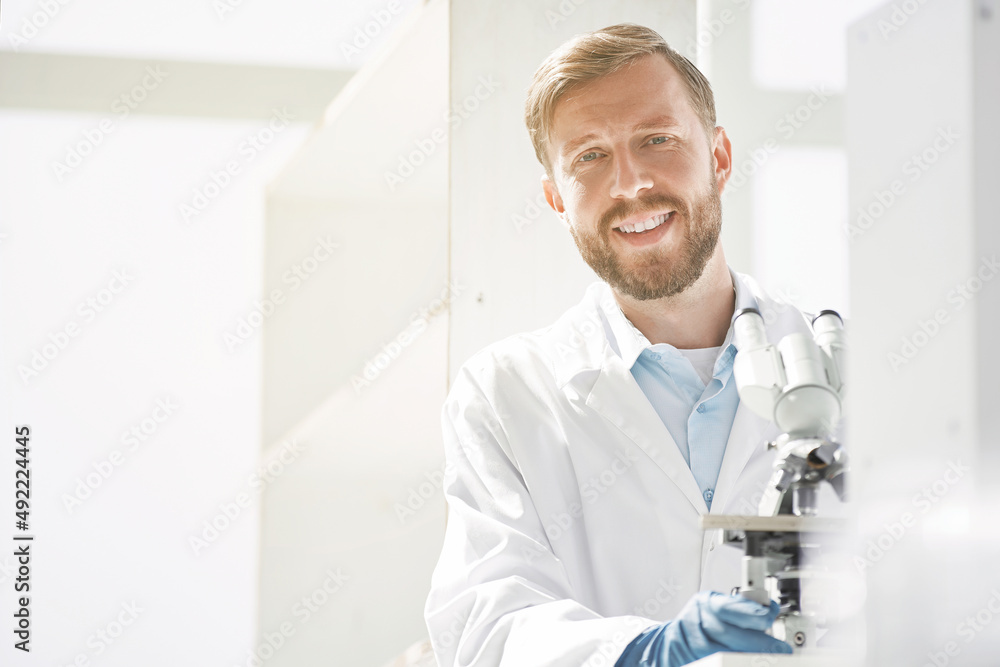 smiling scientist sitting at a laboratory table.