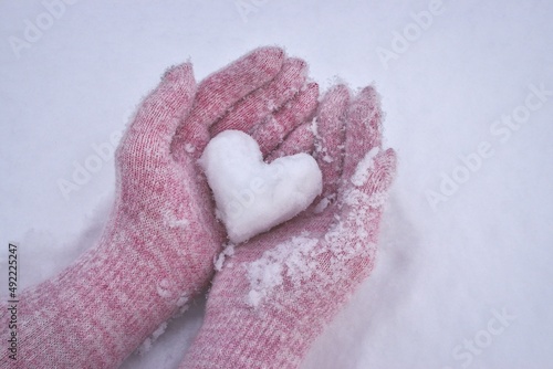 Winter conceptual photo. Heart of snow in female hands.