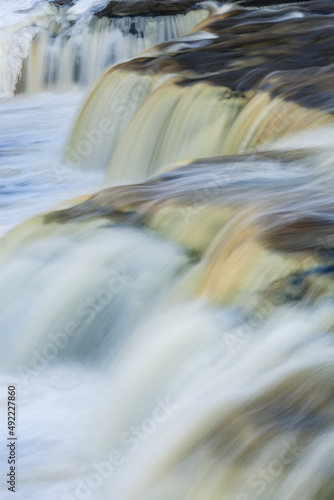 Winter landscape of Lower Tahquamenon Falls framed by ice and captured with motion blur, Michigan's Upper Peninsula, USA