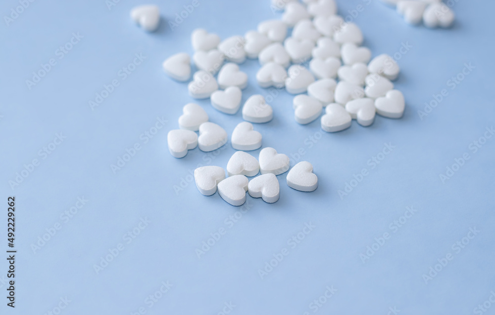 cute little heart shape pills on light blue background. empty space for text, copy paste. Medicines for the heart disease and for blood vessels , lungs. heart shape from little hearts or chaotic 