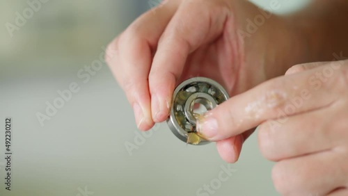 Worker use finger to put lithium grease into small bearing at laboratory. Yellow transparance grease on the finger. Testing and service concept. Preventive maintenance and checking bearing damage