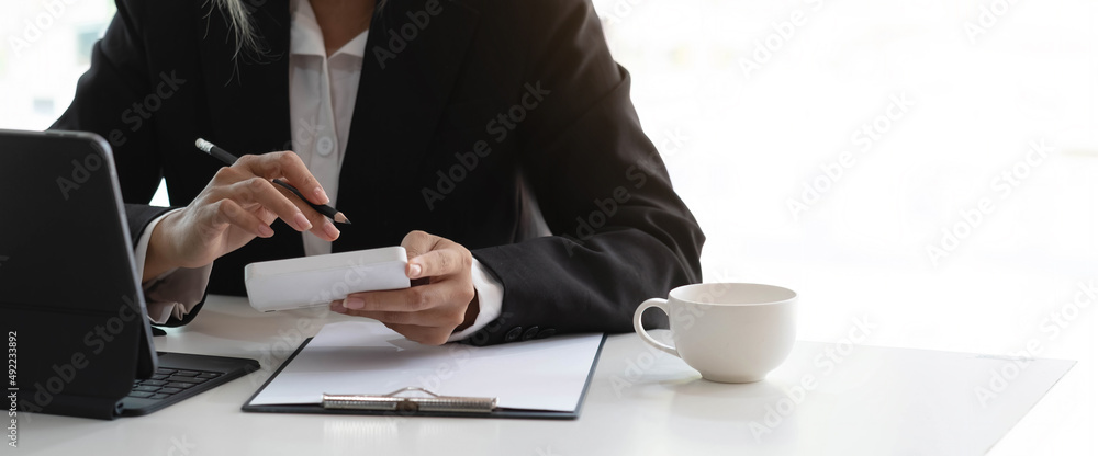 Business woman using calculator and writing make note with calculate. Woman working at office with laptop and documents on his desk Business woman using calculator and writing make note with calculate. Woman working at office with laptop and documents on his desk