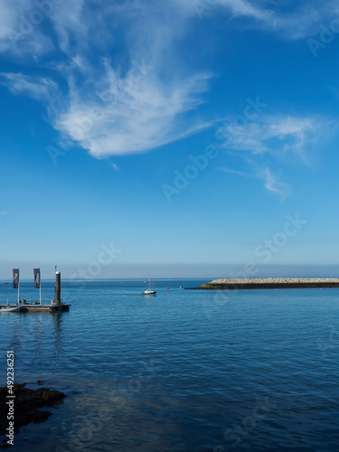 Still  limpid  glassy waters in a harbour on the Isle of Wight  ready to receive a distant yacht making its way under a deep blue sky.