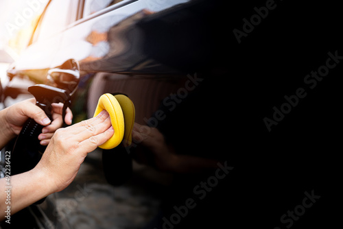 Car clean concept, Hand a man holding a sponge and clean spray wax to take care of the surface of the car from washing