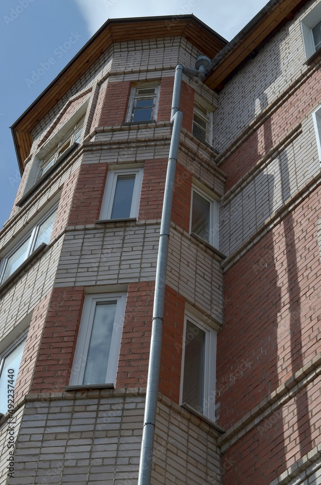 Perspective of a high-rise building, bottom-up view. Beautiful brick building with windows. The sky is above. Perspective of a high-rise building, bottom-up view. Beautiful brick building with windows. The sky is above.