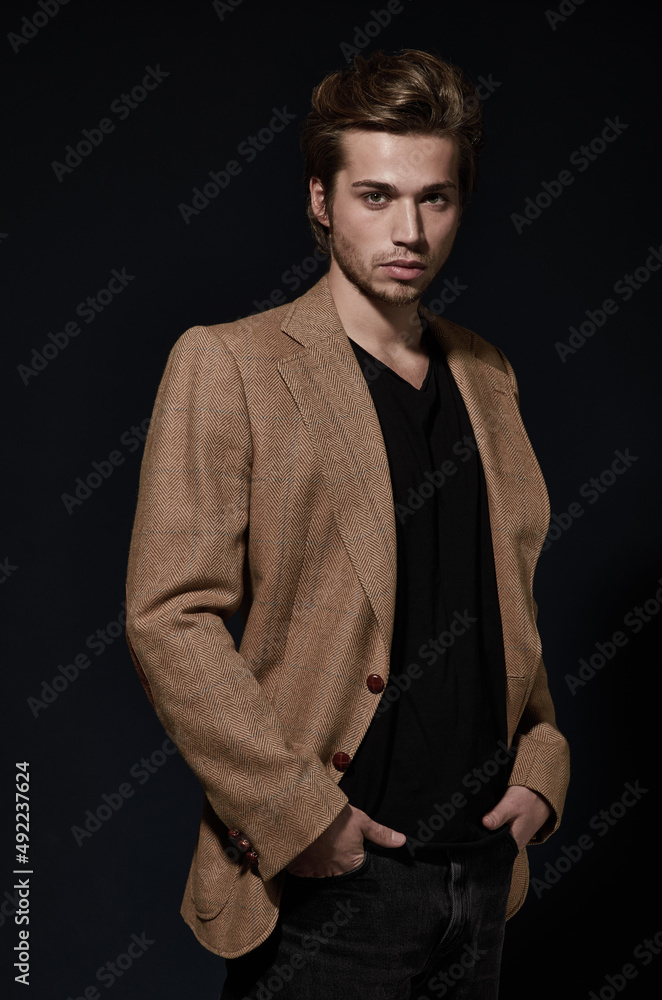 Model of style and poise. A handsome young model wearing a smart jacket posing against a black background.