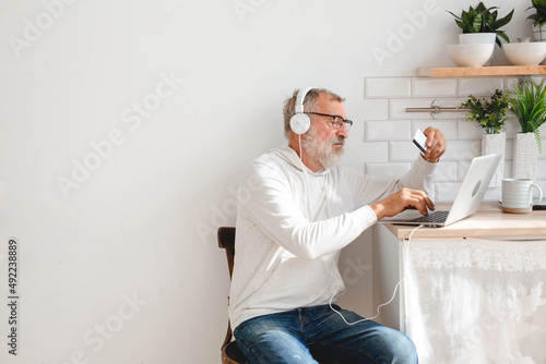 Senior elderly man at laptop paying with credit card for online shopping - copy space and place for advertising