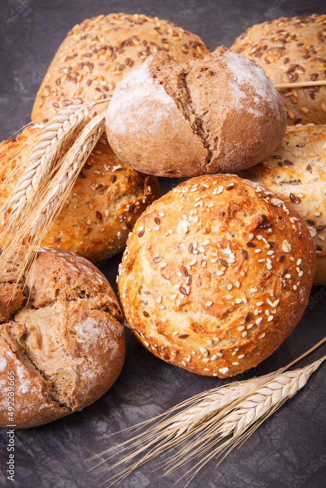 Fresh baked rolls with seeds and ears of rye or wheat grain Fresh baked rolls with seeds and ears of rye or wheat grain