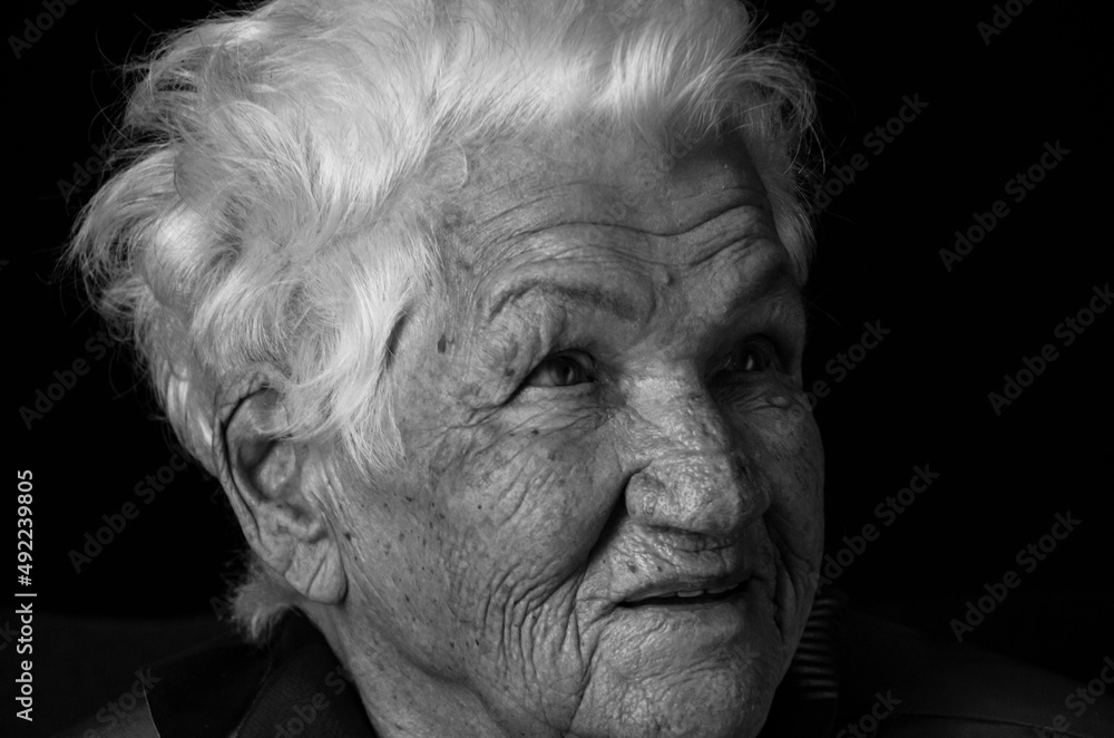Portrait of serious senior woman against black background. Black and white photo. Portrait of serious senior woman against black background. Black and white photo.