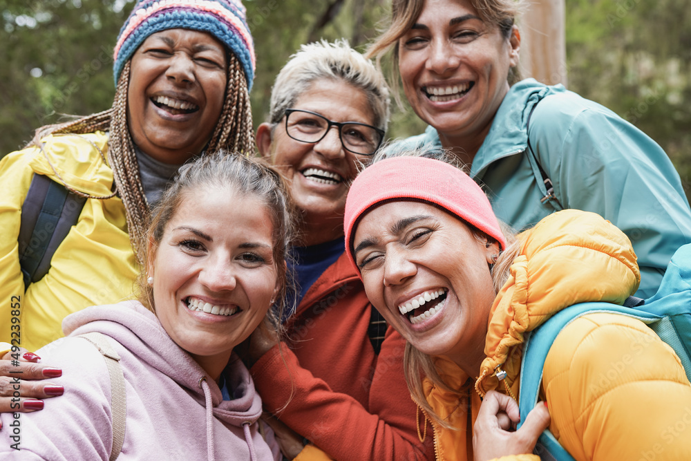 Multiracial women having fun taking a selfie during trekking day at the mountain forest