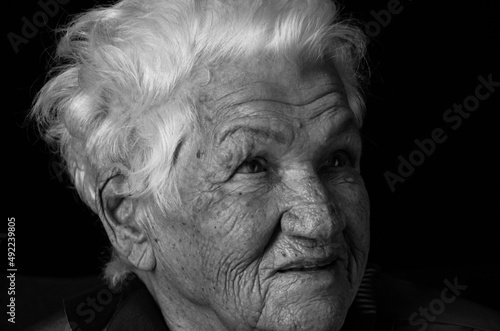 Portrait of serious senior woman against black background. Black and white photo.
