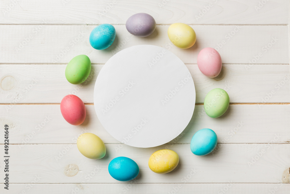 round frame multicolored Easter eggs with white blank paper on a brown background, close-up, space for text, blank for design, selective focus, tinted image round frame multicolored Easter eggs with white blank paper on a brown background, close-up, space for text, blank for design, selective focus, tinted image