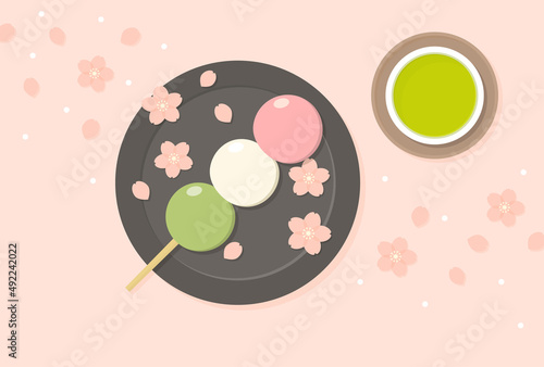 お皿にのせた三色団子とお茶の上に舞い散る桜の花 - 春・お花見・和菓子・スイーツのイメージ素材