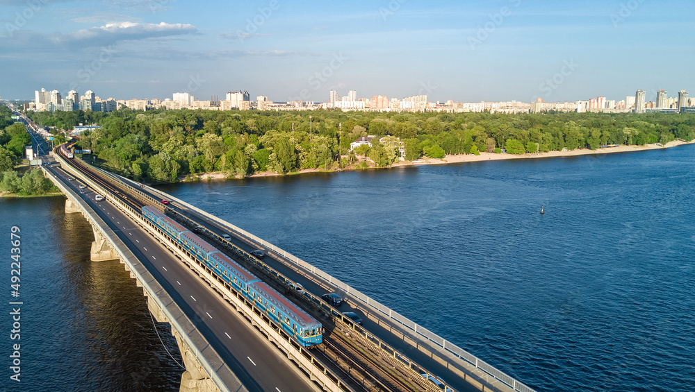 Kyiv cityscape aerial drone view from above, Metro railway bridge with train and Dnieper river from above, skyline of city of Kiev and Dnipro, Ukraine